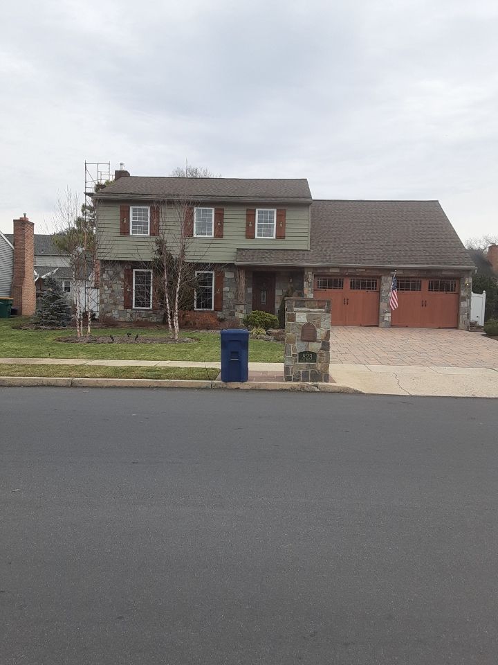 Suburban two-story house with brick facade, attached garage, driveway, and blue mailbox by the street