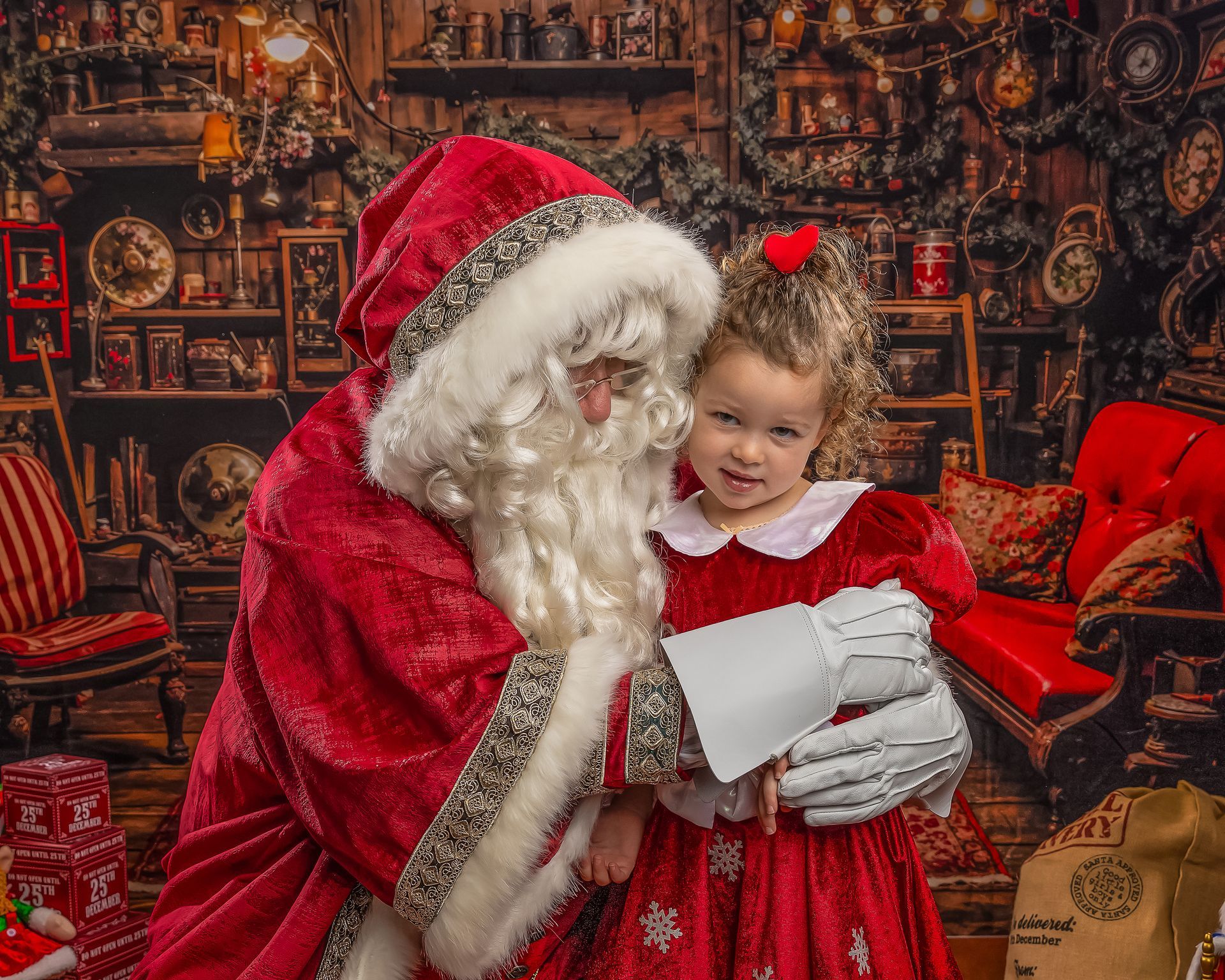 Boy laughs with Santa Claus, sitting next to a Christmas tree.