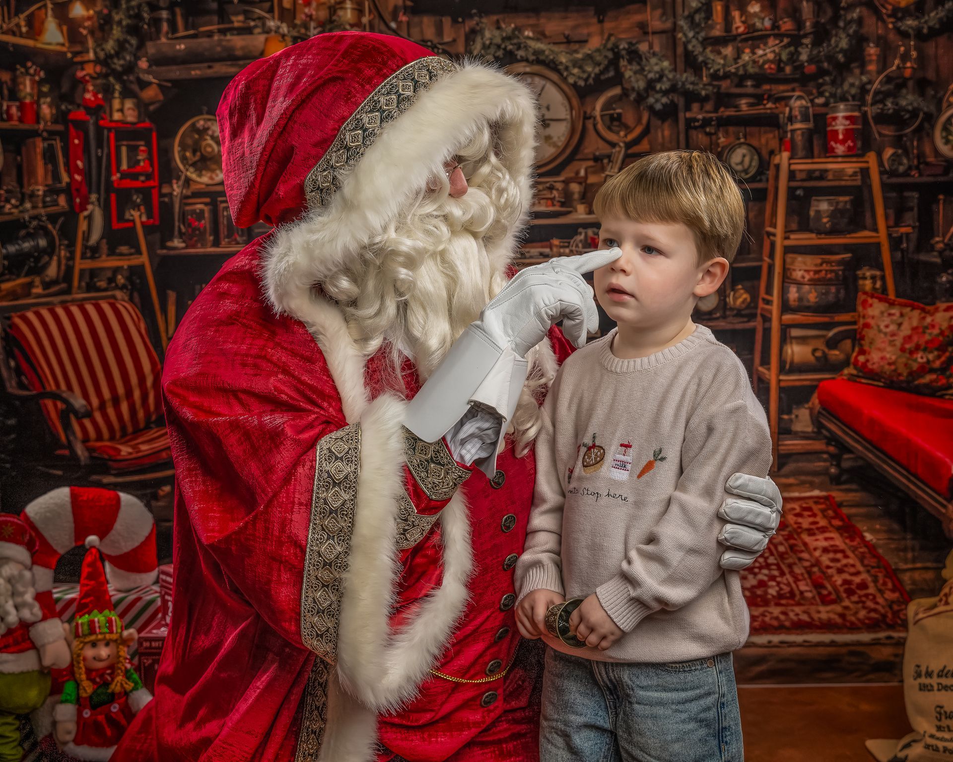 Santa with two children and a woman, looking at stockings, in a decorated room.