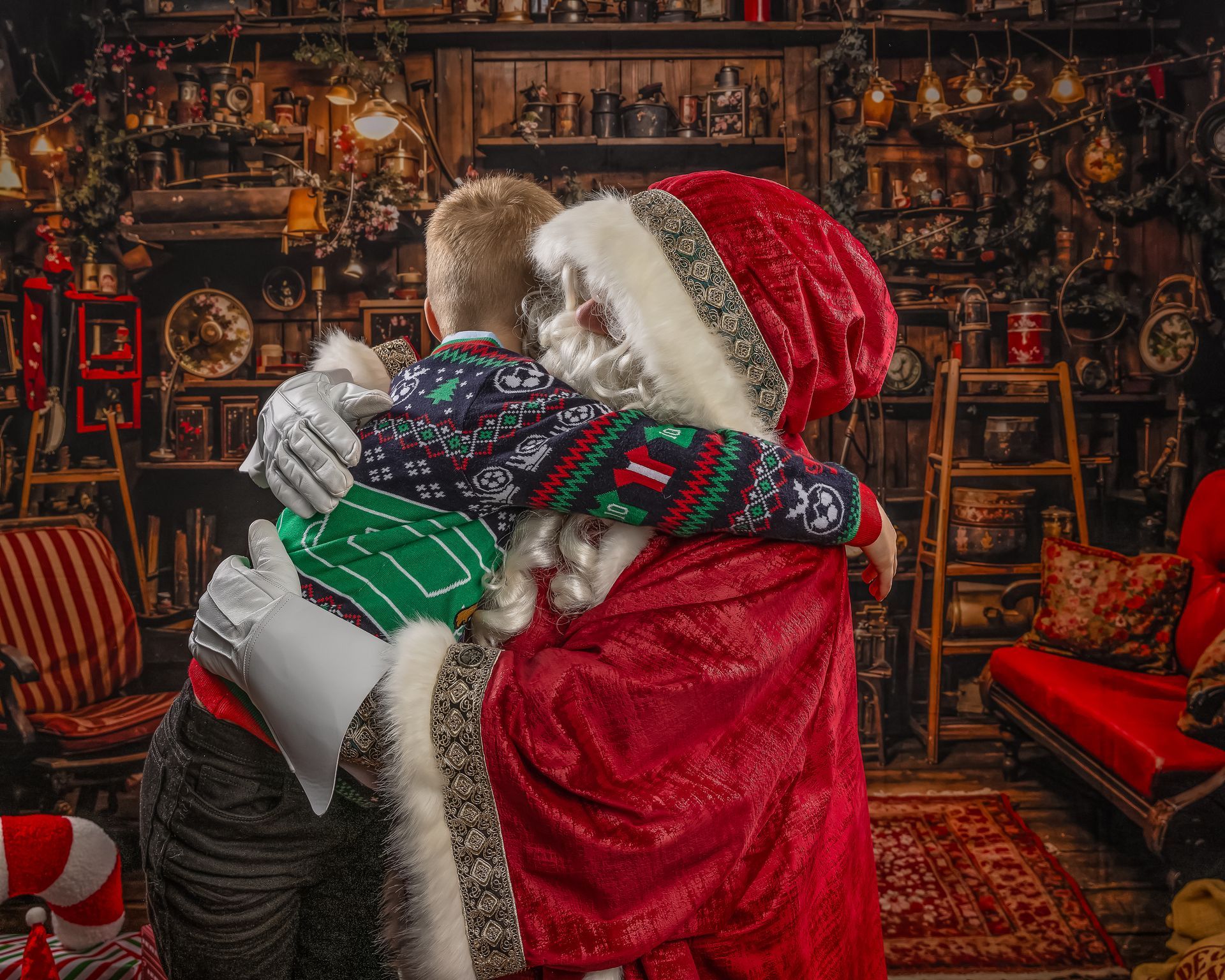 Santa Claus with a baby and a toddler, the toddler touching Santa's nose. Red and white outfits.