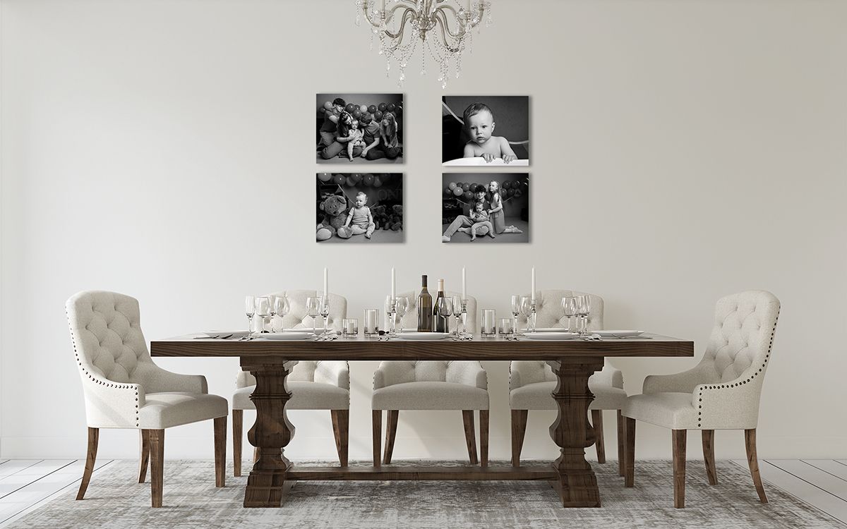 Dining room with a dark wood table, white chairs, and four framed black and white baby photos.