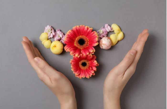 Handen omlijsten kleurrijke bloemen die in de vorm van een hart zijn gerangschikt op een grijze achtergrond.
