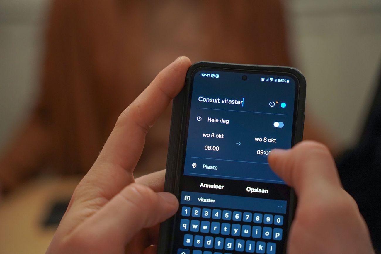 Handen die een smartphone vasthouden met een donker scherm en een open virtueel toetsenbord.