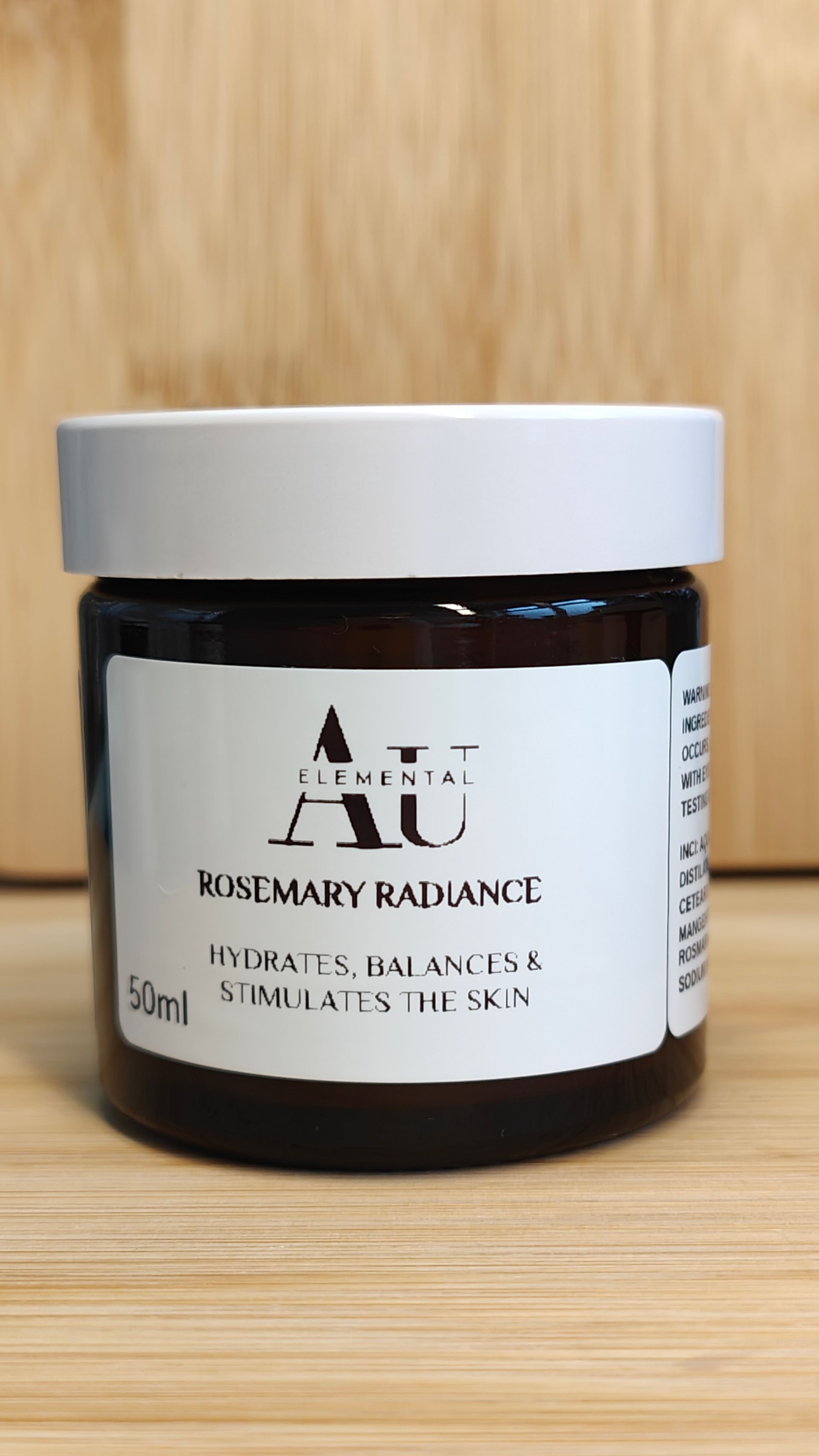 Jar of AU Elements Rosemary Radiance skincare product, with label and white lid.