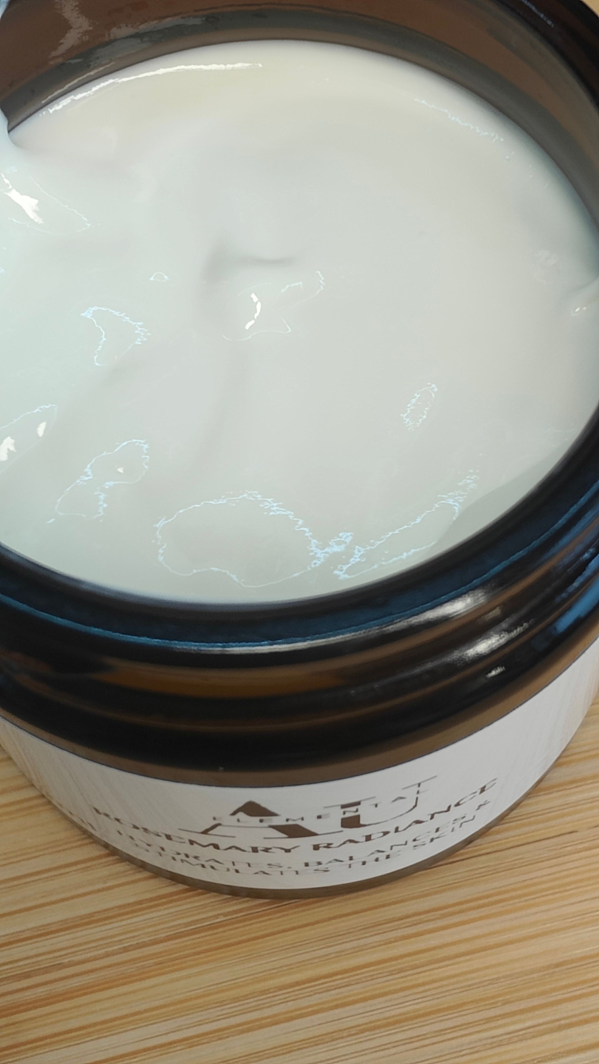 Jar of AU Elements Rosemary Radiance skincare product, with label and white lid.