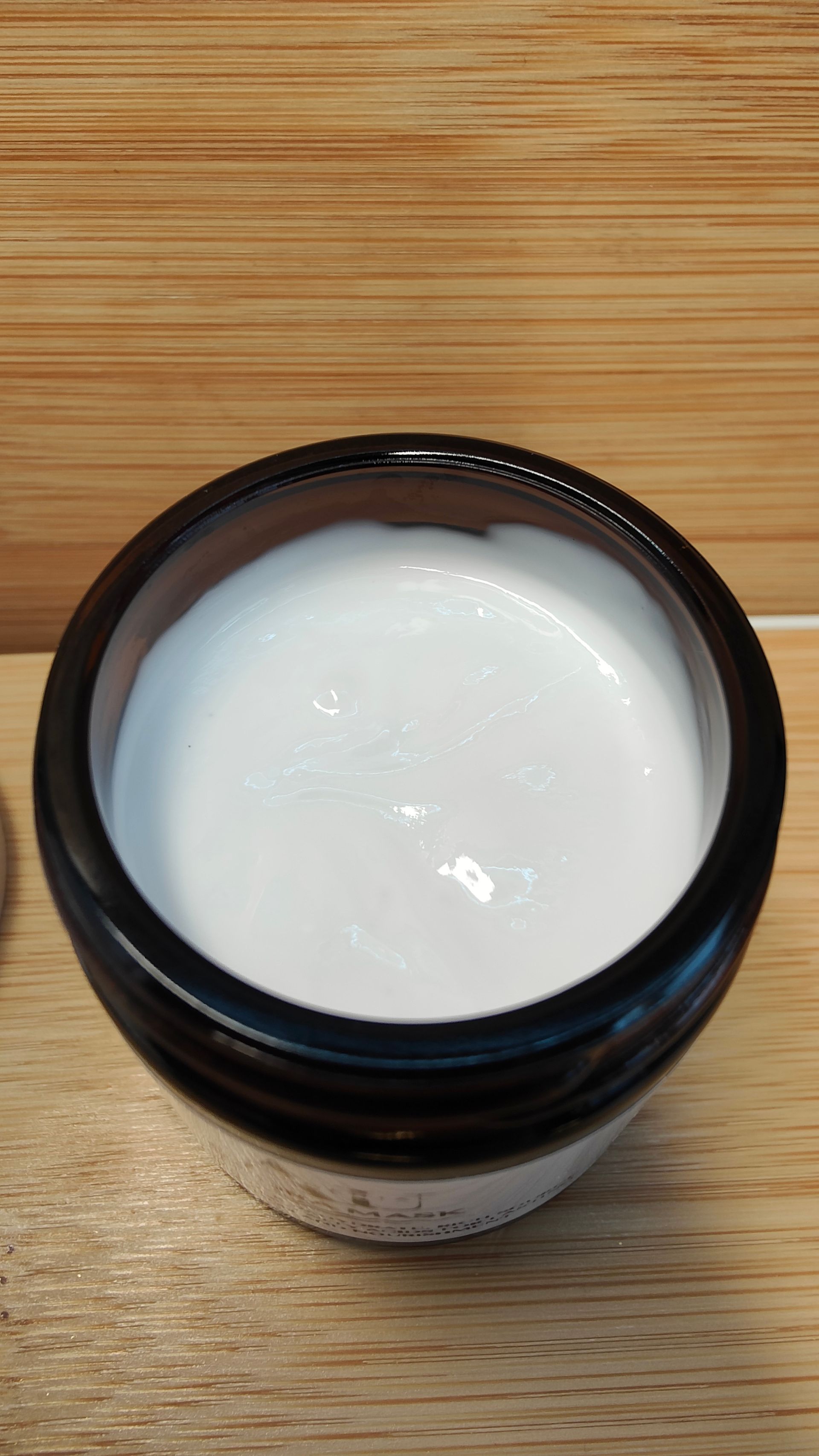 Jar of AU Elemental Hydra Mask with a white label, on a wooden surface.