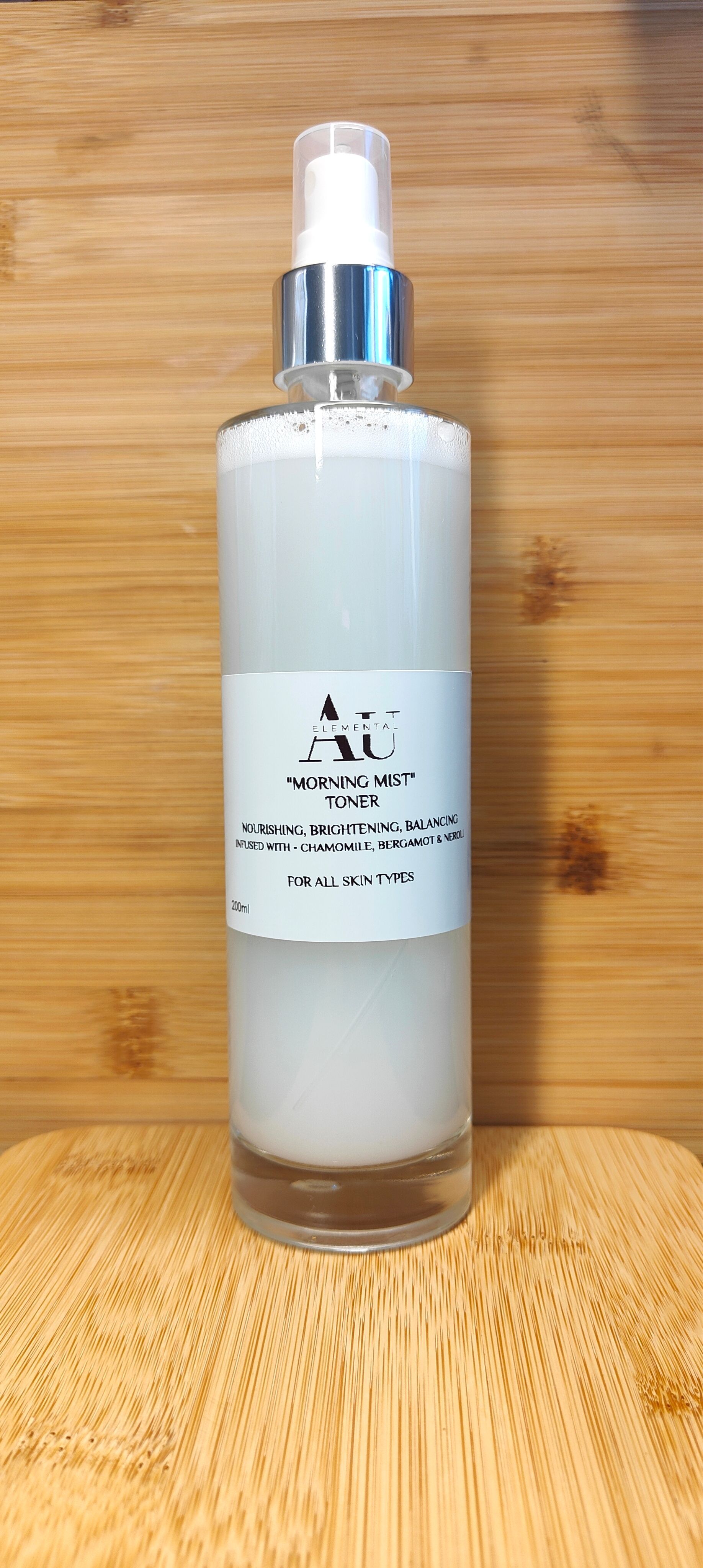 A glass bottle with a white liquid and a label, sitting on a wooden surface.