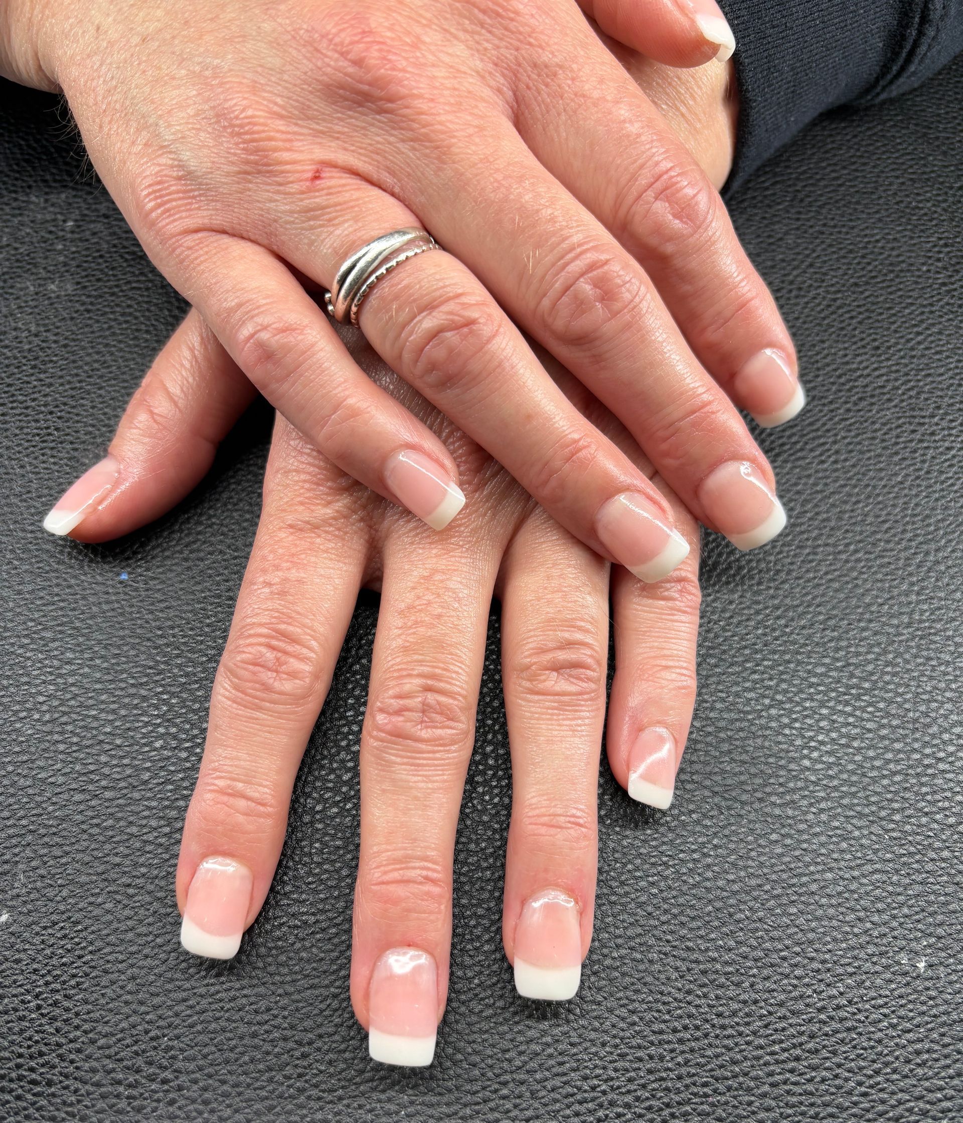 A woman 's hands with french manicure and a ring on her finger