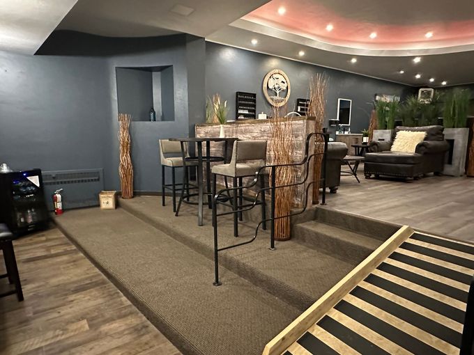 A living room with a staircase leading up to a bar.