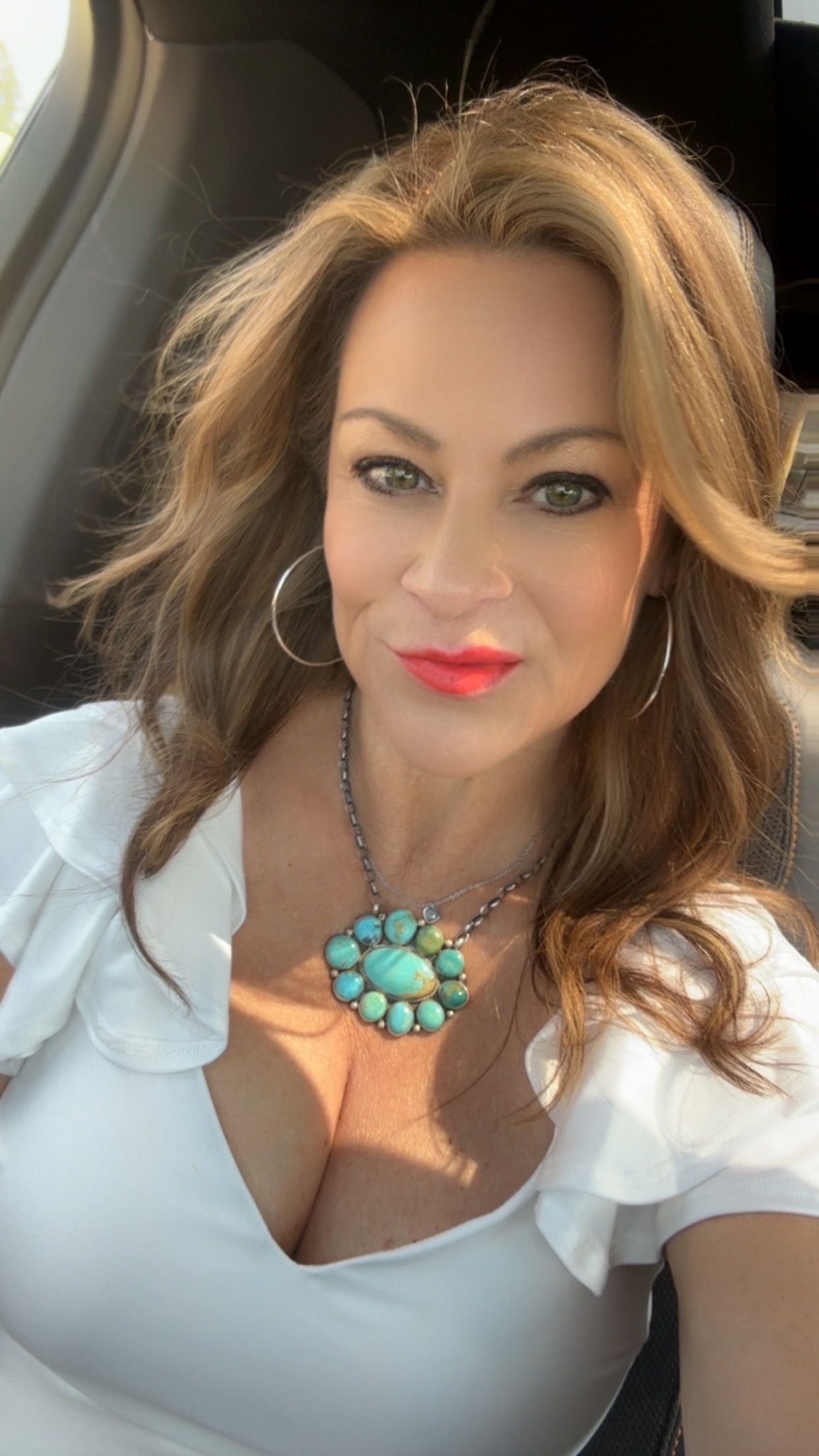 A woman is taking a selfie in the back seat of a car.