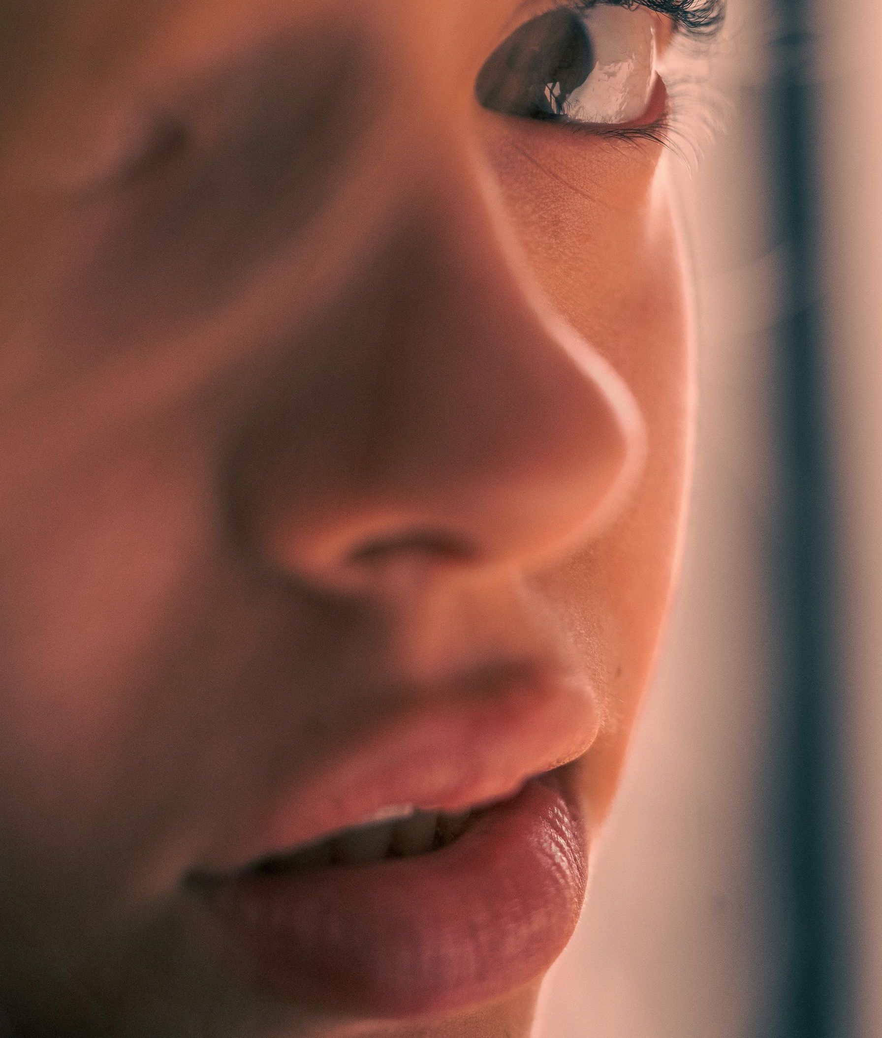 Close-up of a person's face looking off to the side. Soft lighting, warm tones.