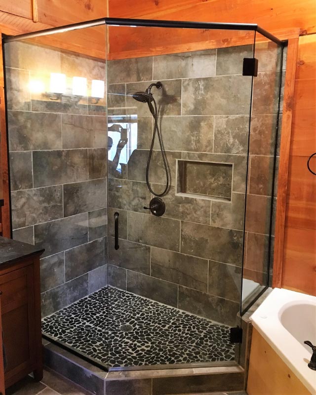 A bathroom with a walk in shower with a glass door.