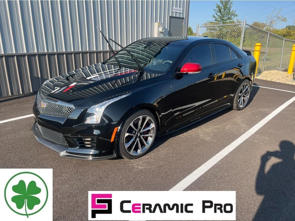 Black Cadillac sedan with Ceramic Pro logo parked outside a building