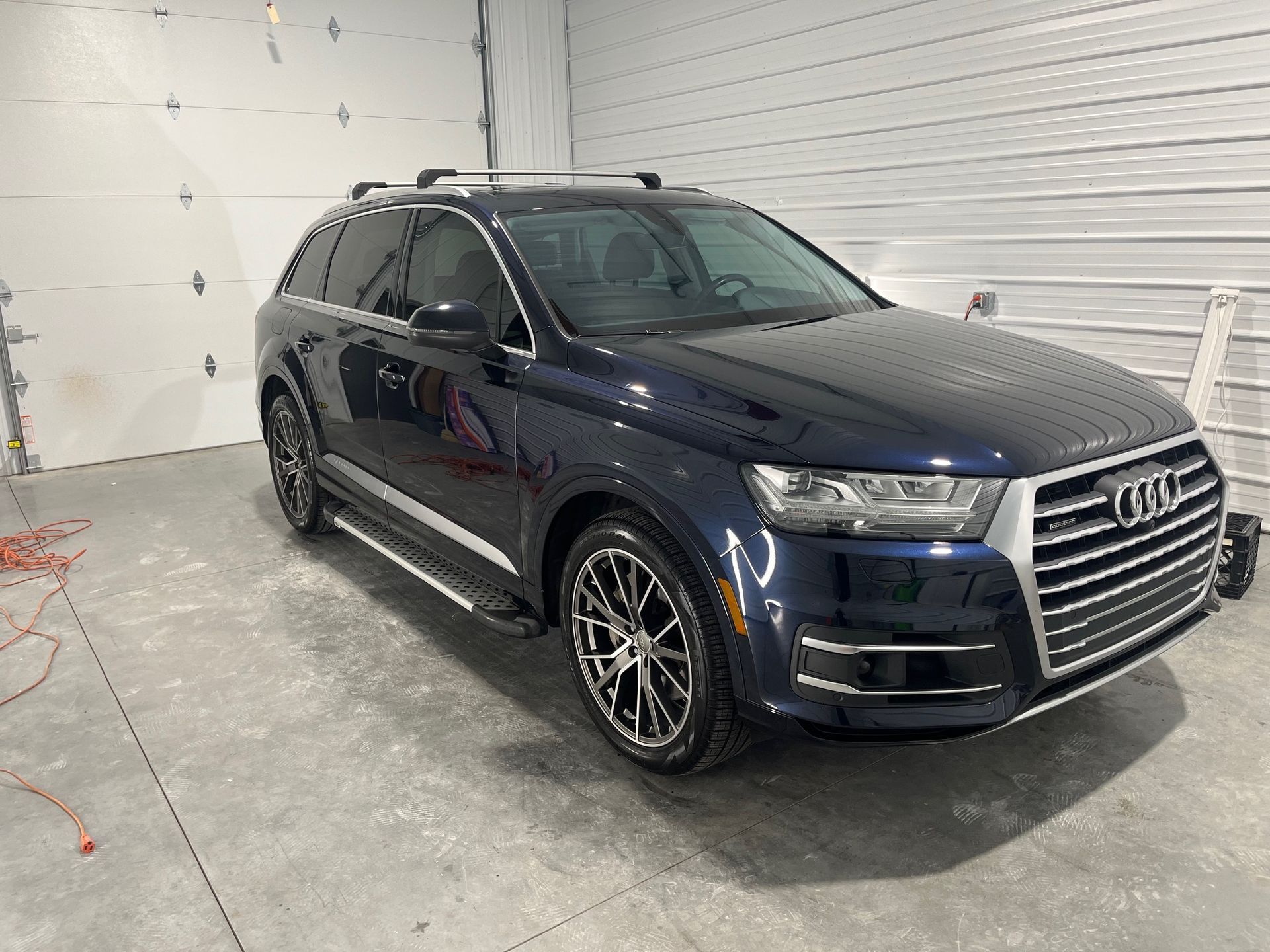 Dark blue Audi SUV parked inside a white garage, front three-quarter view