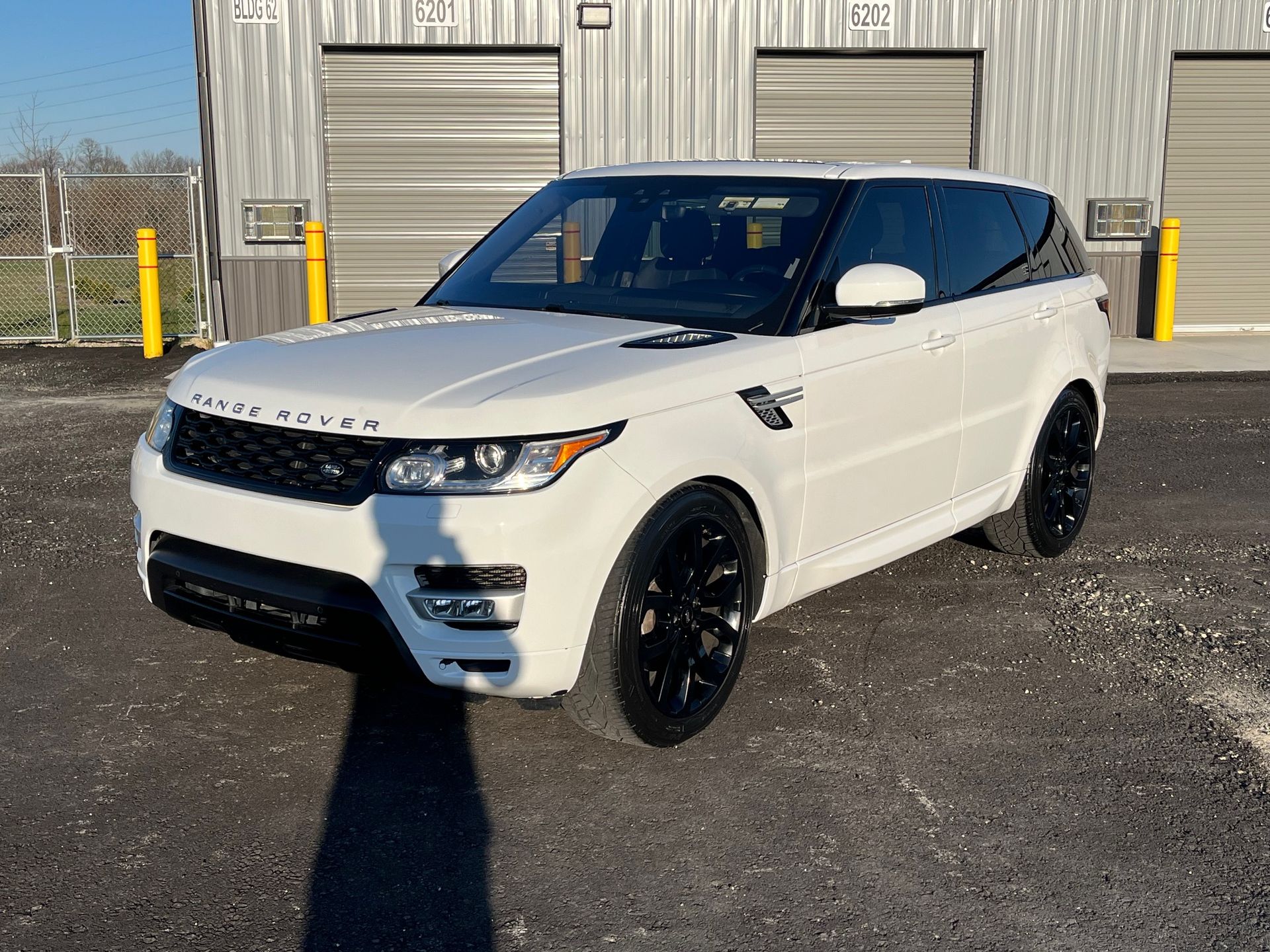 A white range rover sport is parked in front of a building.