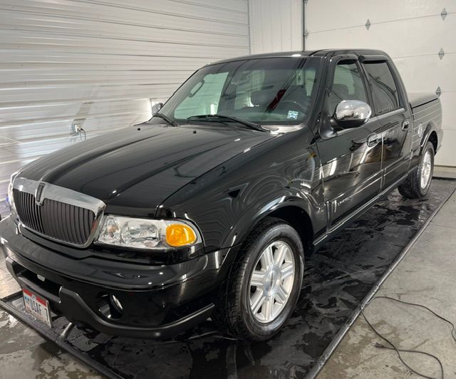 Black pickup truck parked indoors on a wet floor in a garage or wash bay