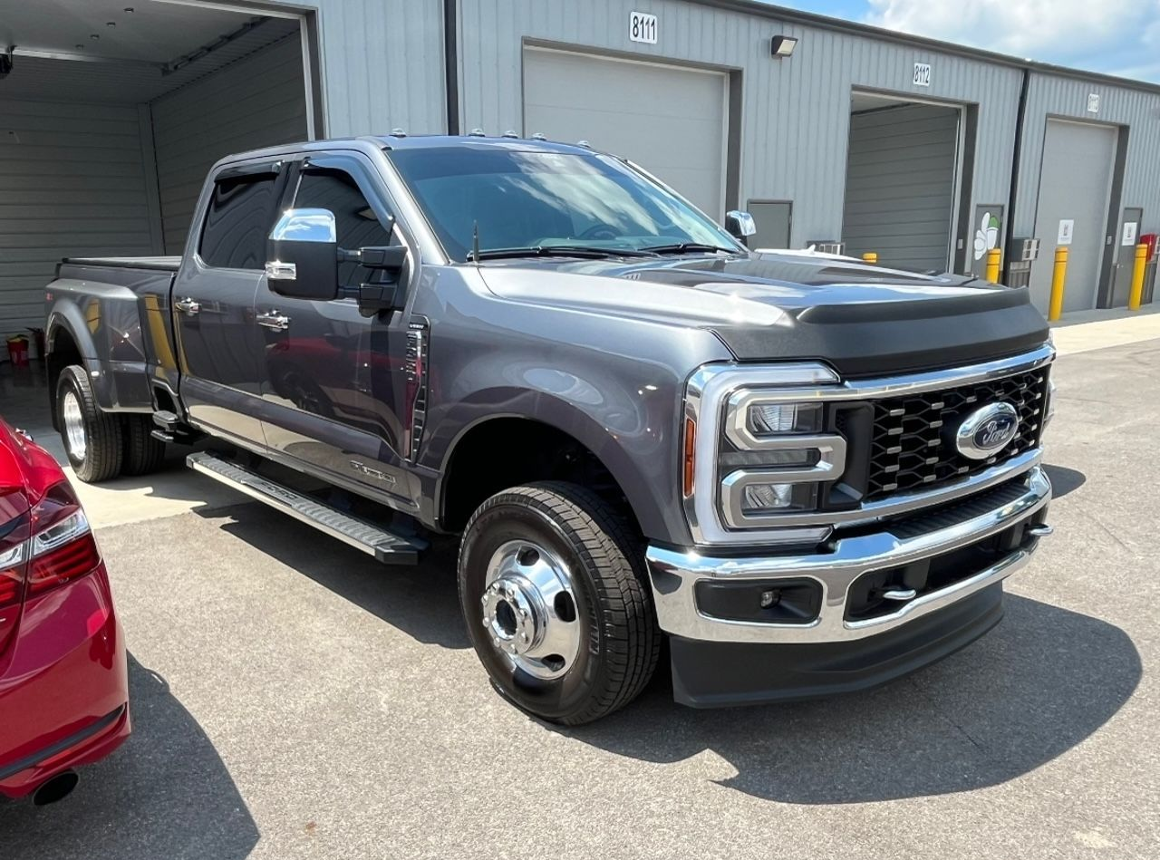 Gray Ford pickup with flatbed trailer parked outside a warehouse door