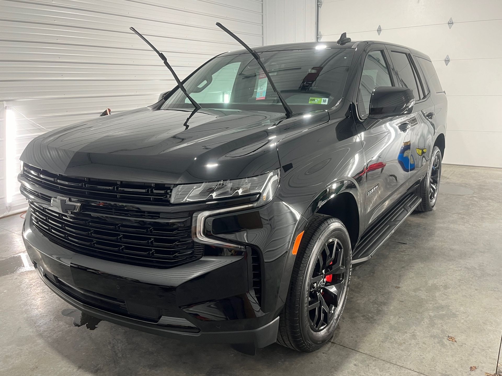 Black SUV parked indoors in a showroom, front-left view, with tinted windows and black wheels
