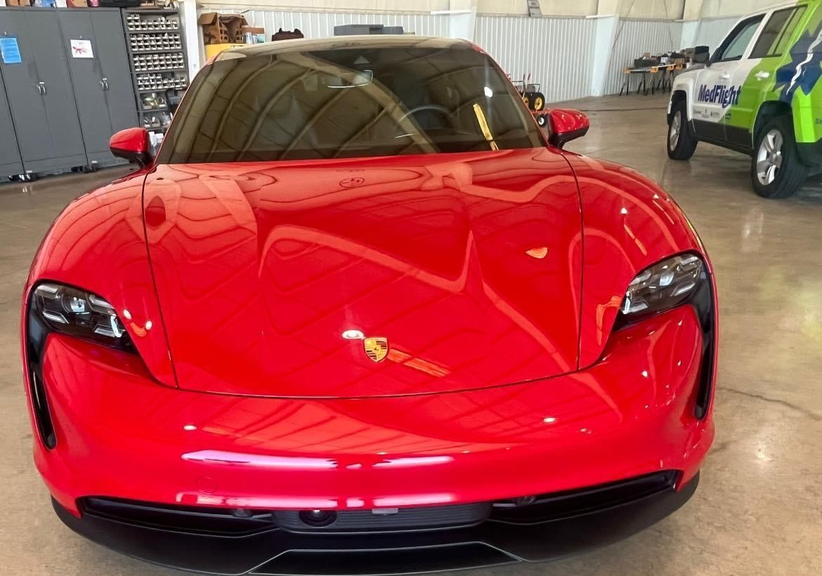 Blue car body panel showing glossy one-step paint correction under bright shop lights