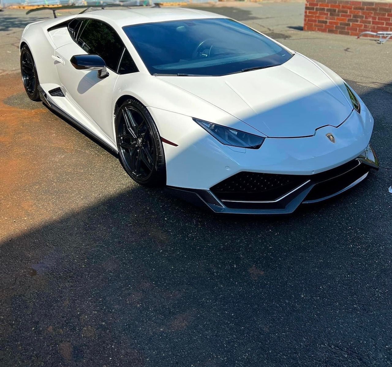 White Lamborghini sports car parked on pavement, front three-quarter view