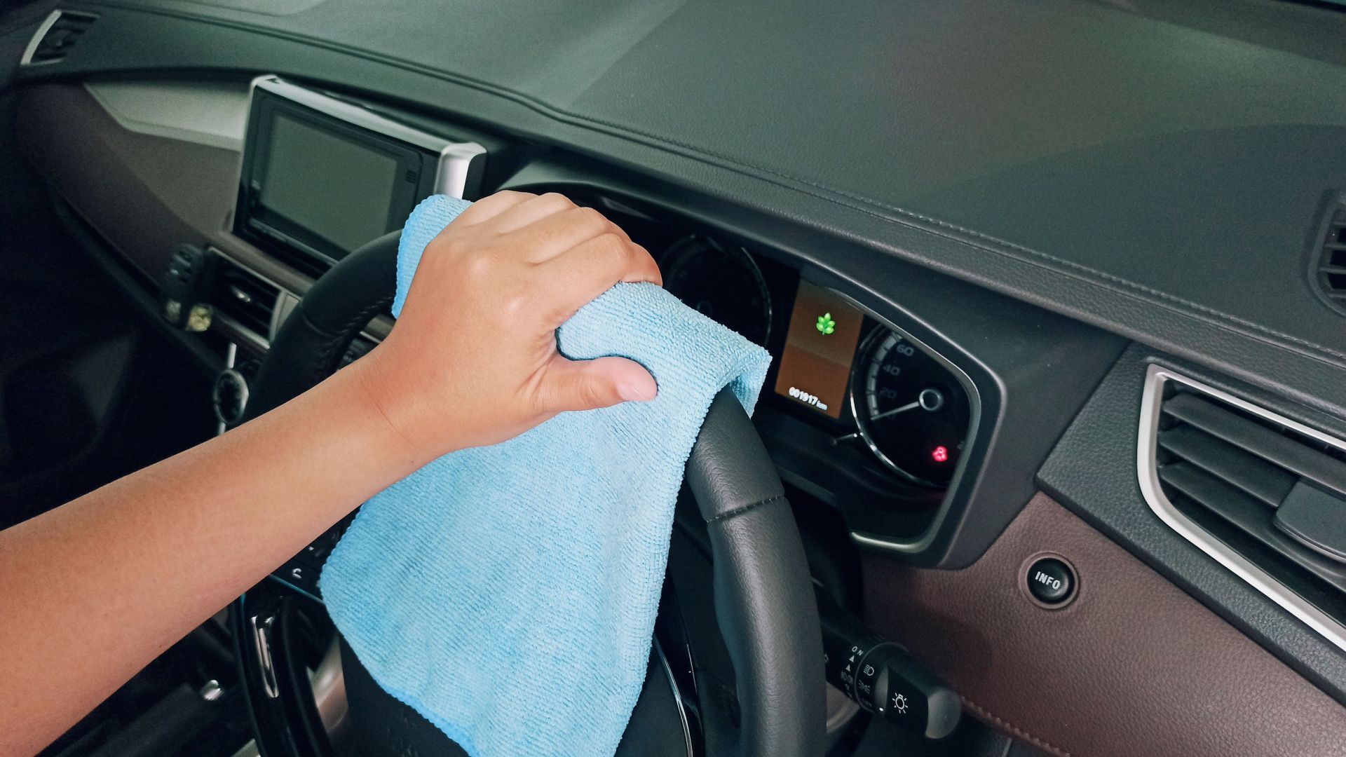 Person polishing a black car fender with a handheld buffer.