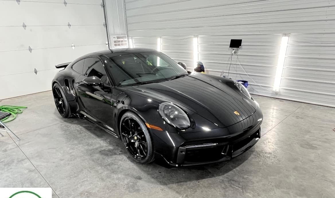 Black sports car parked in a bright garage, front three-quarter view