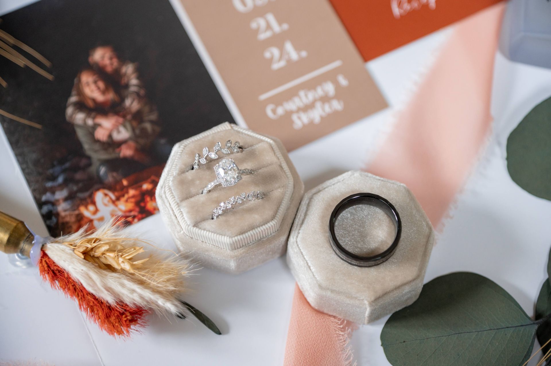 A couple of rings are sitting on top of a table next to a wedding invitation.