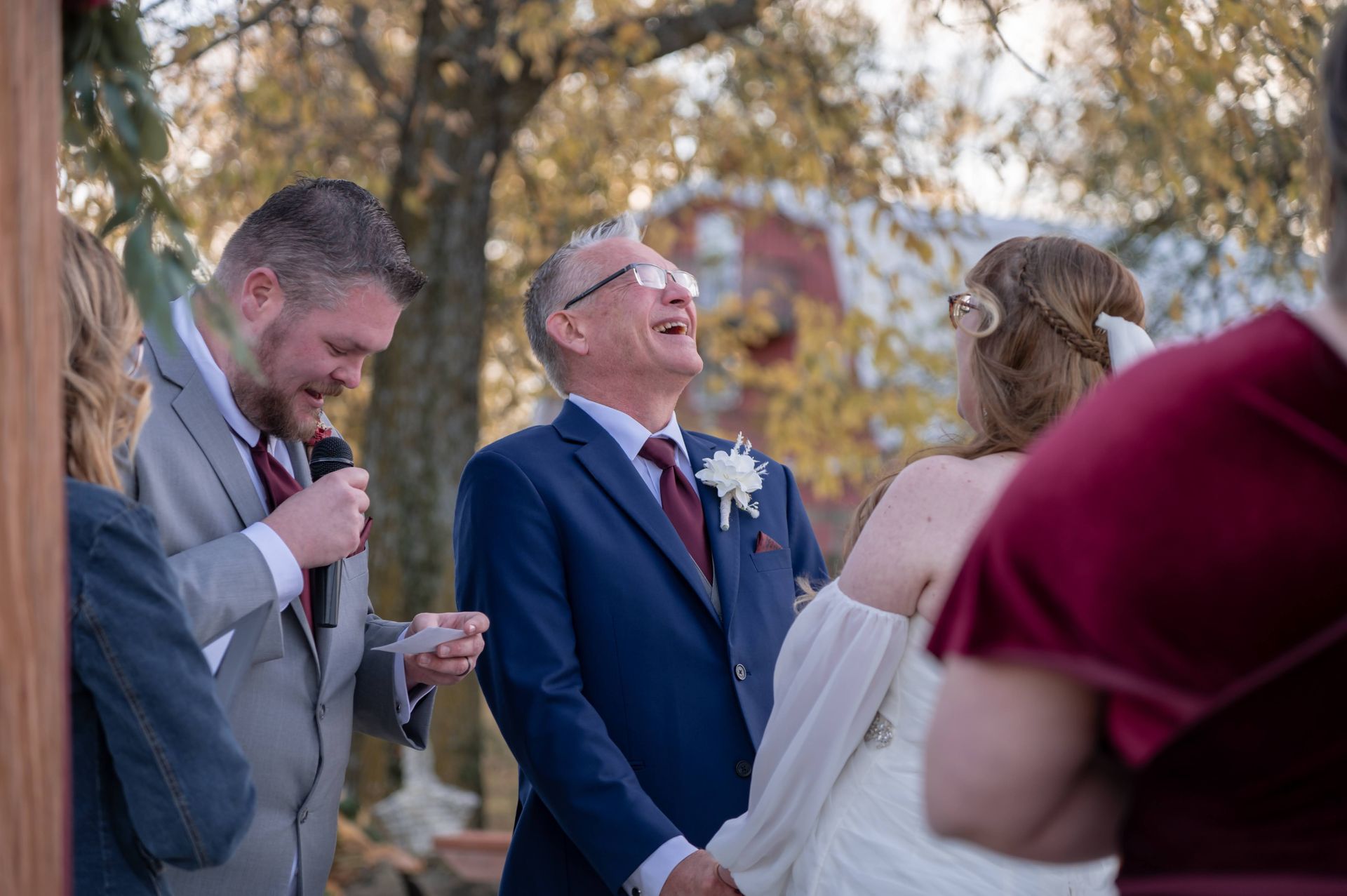 A bride and groom are laughing while holding hands at their wedding ceremony.