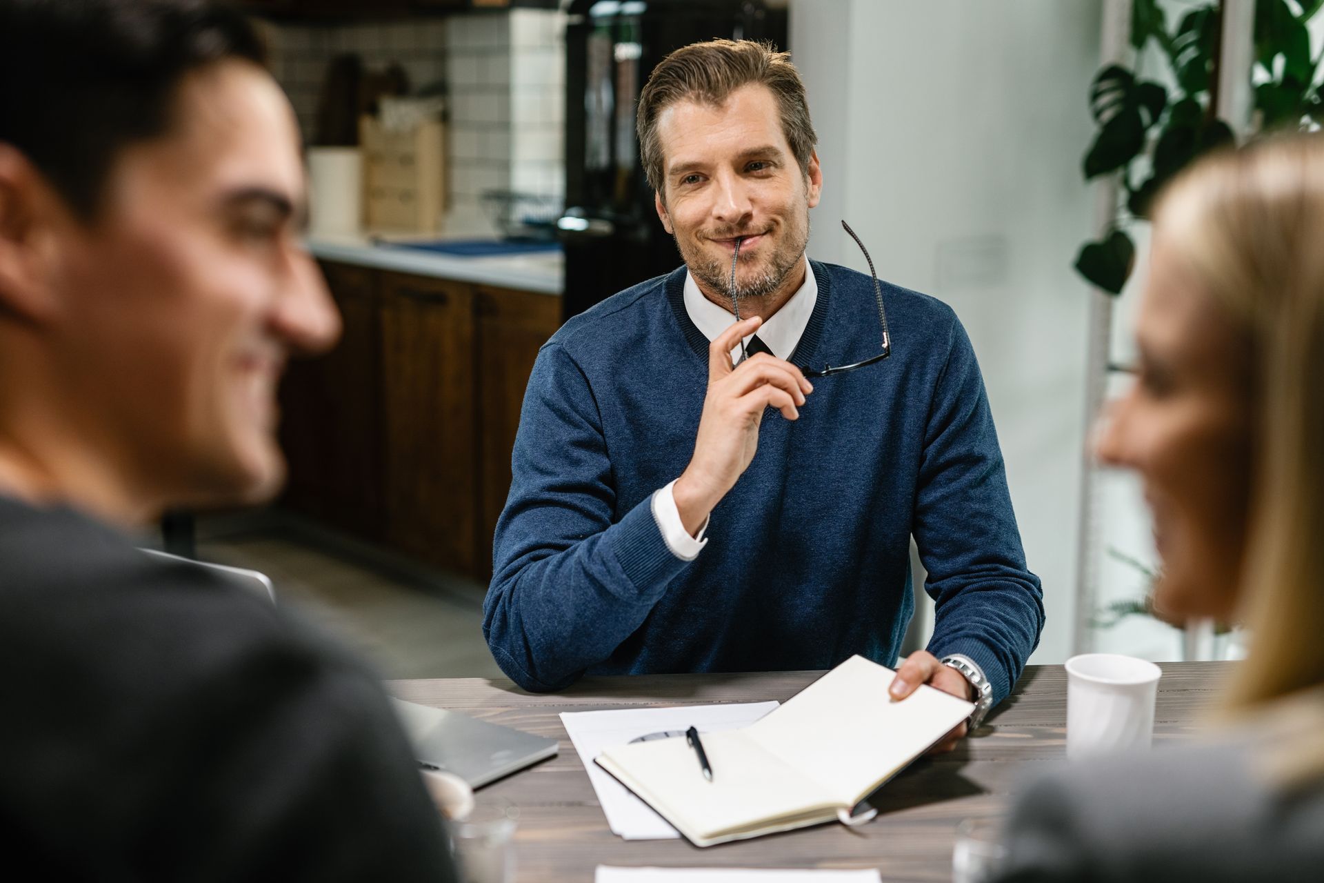 A man is sitting at a table talking to two people.