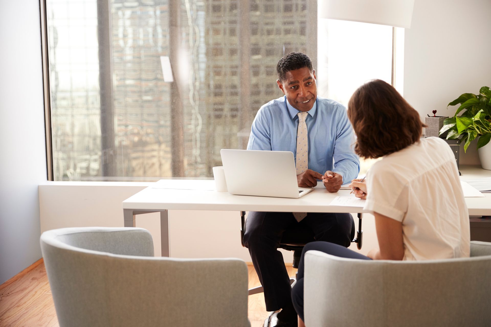 A man and a woman are sitting at a table with a laptop.