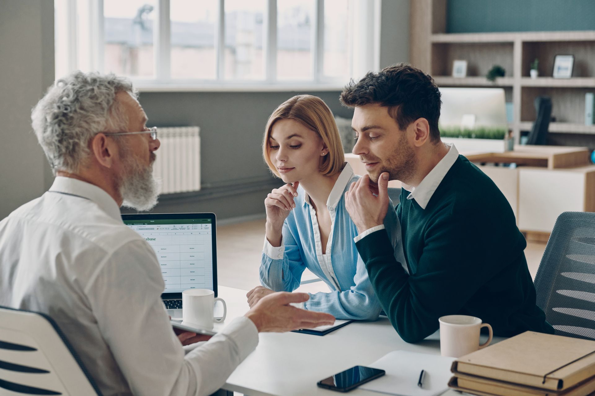 A man is sitting at a table talking to a couple.