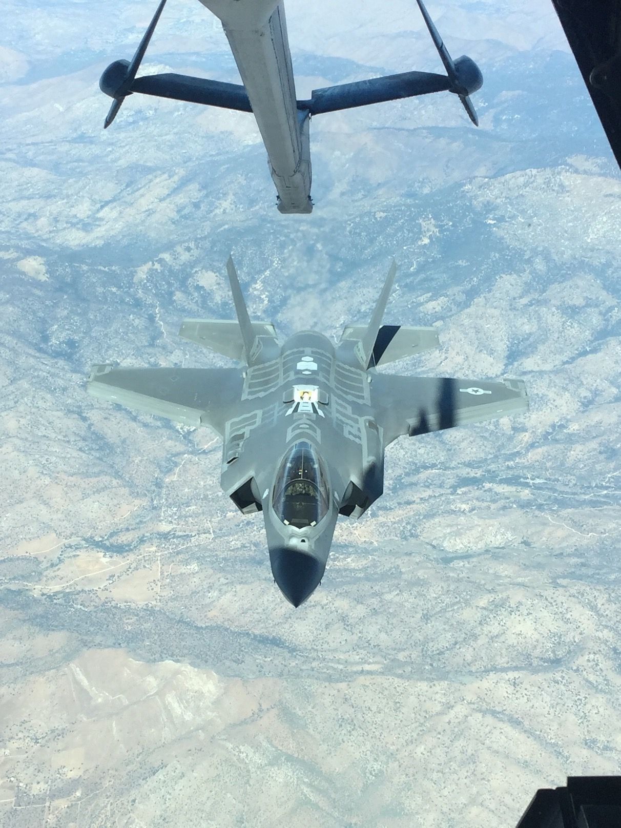 A fighter jet is being refueled by a plane in the sky