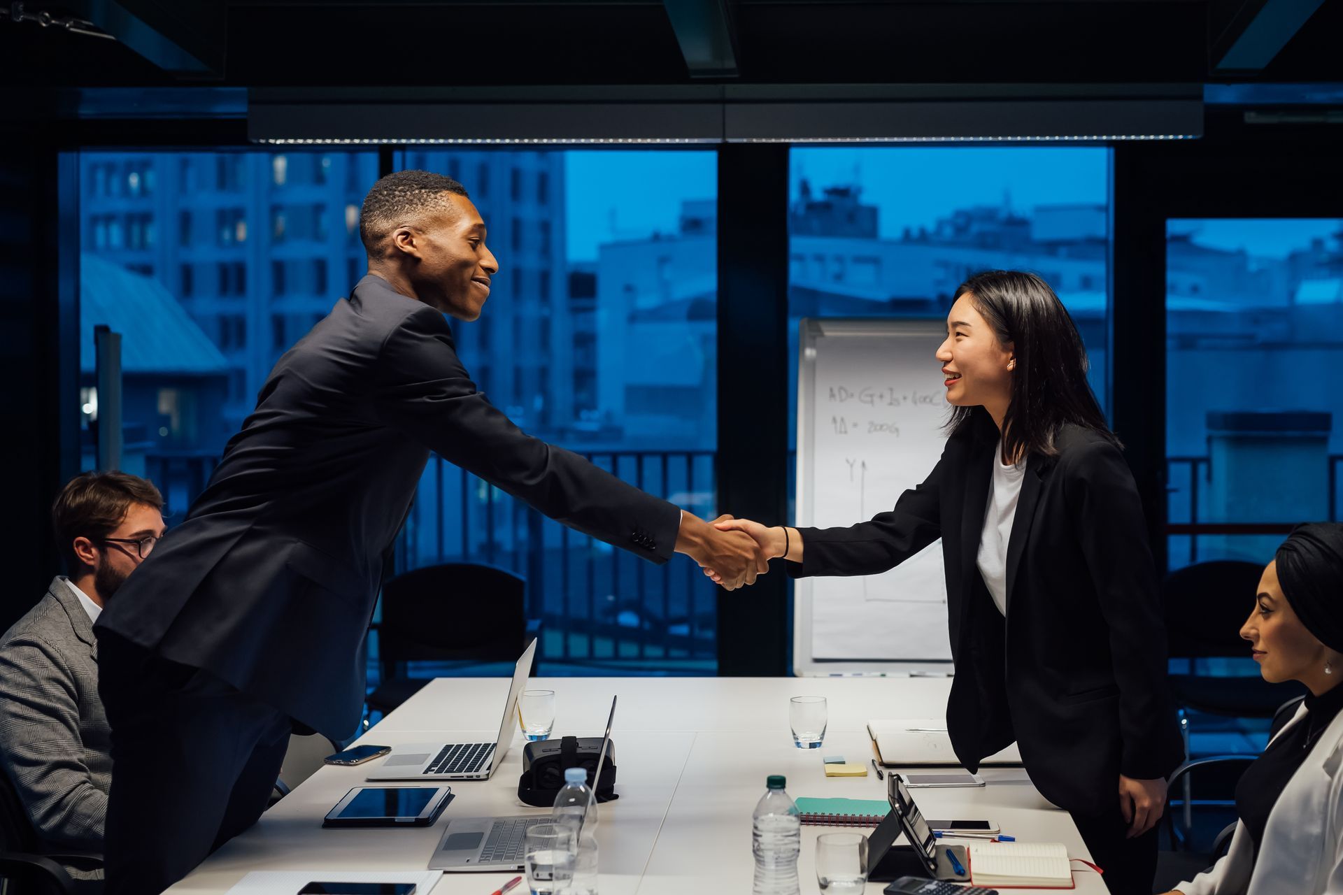 A man and a woman are shaking hands in a conference room.