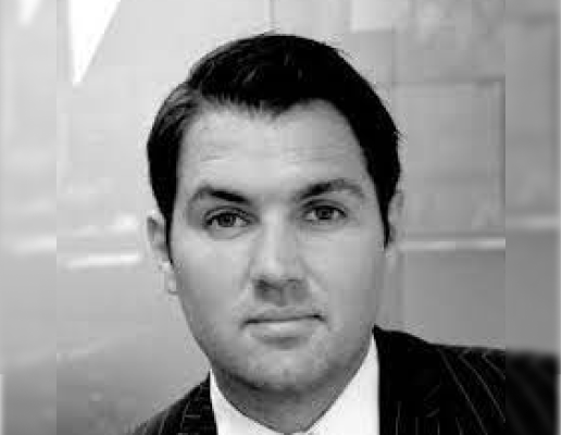 A man in a suit and tie is looking at the camera in a black and white photo.