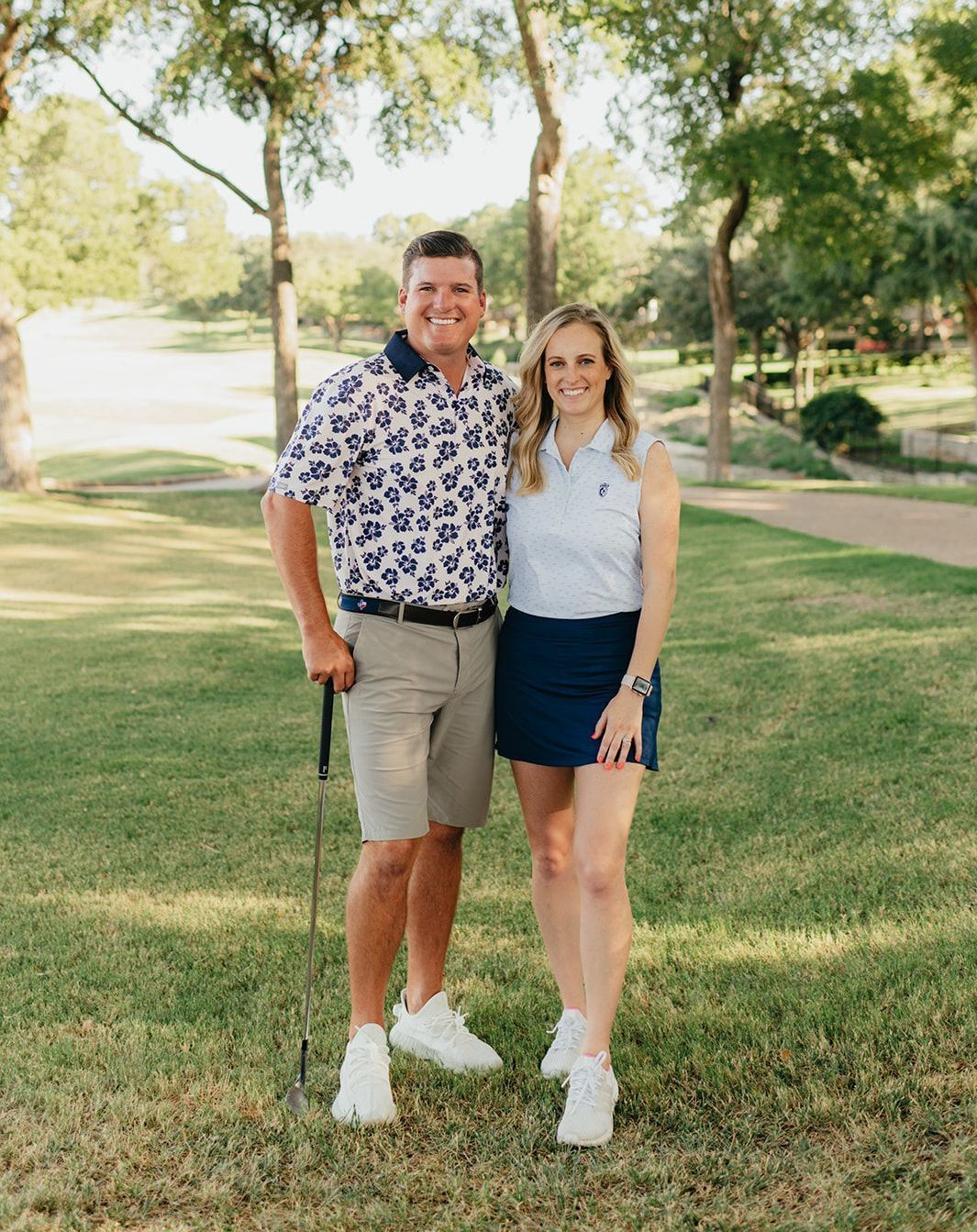 A man and a woman are standing next to each other on a golf course.