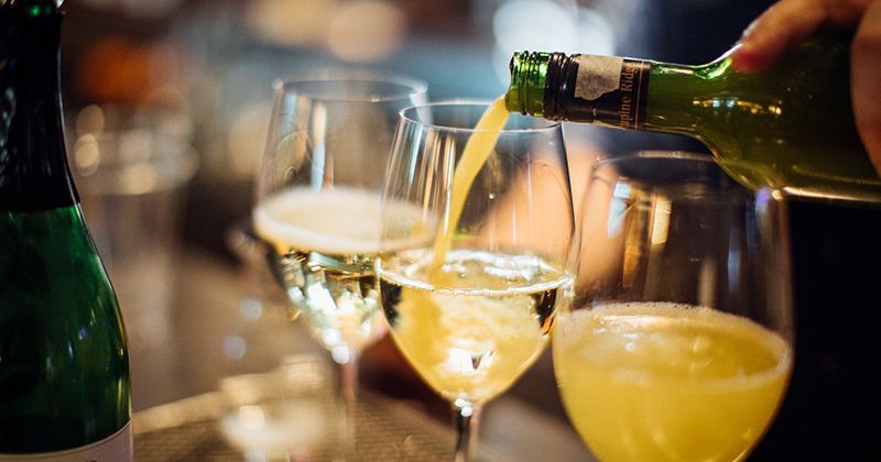 A person is pouring wine into two glasses on a table.