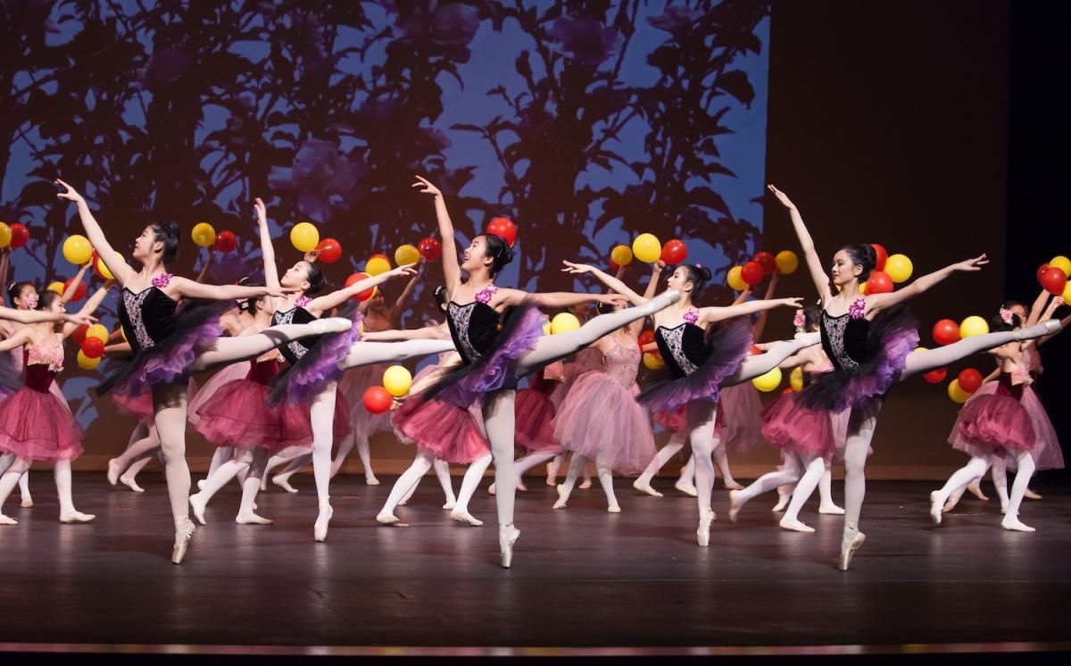 A group of ballerinas are dancing on a stage with balloons.