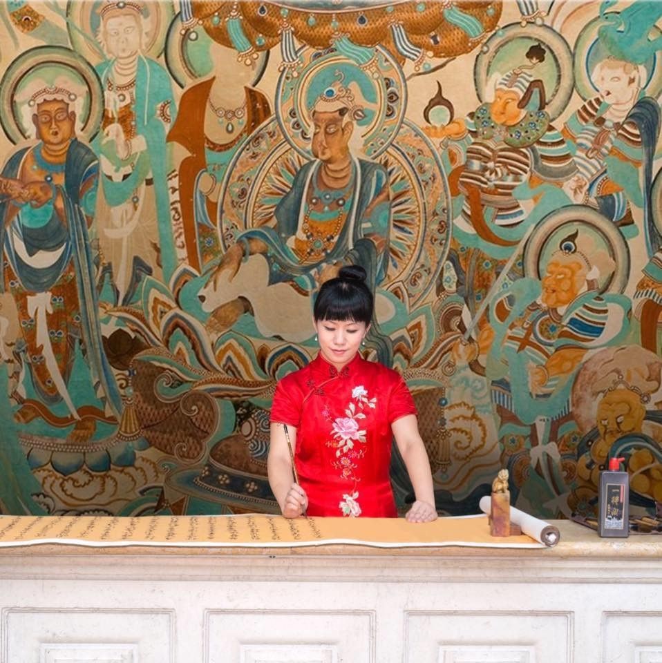 A woman in a red dress is standing in front of a large painting.