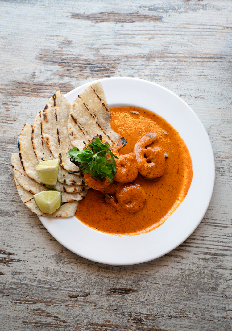 A white plate topped with shrimp and bread on a wooden table.