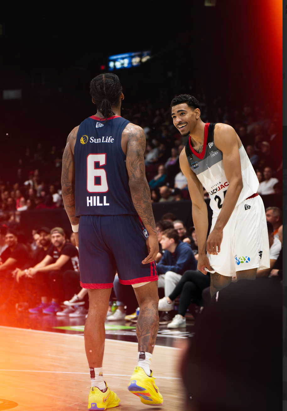 Two basketball players are talking to each other on the court.