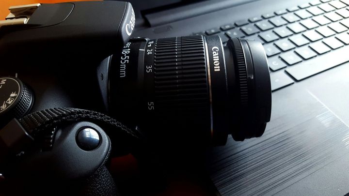 A canon camera is sitting on top of a laptop