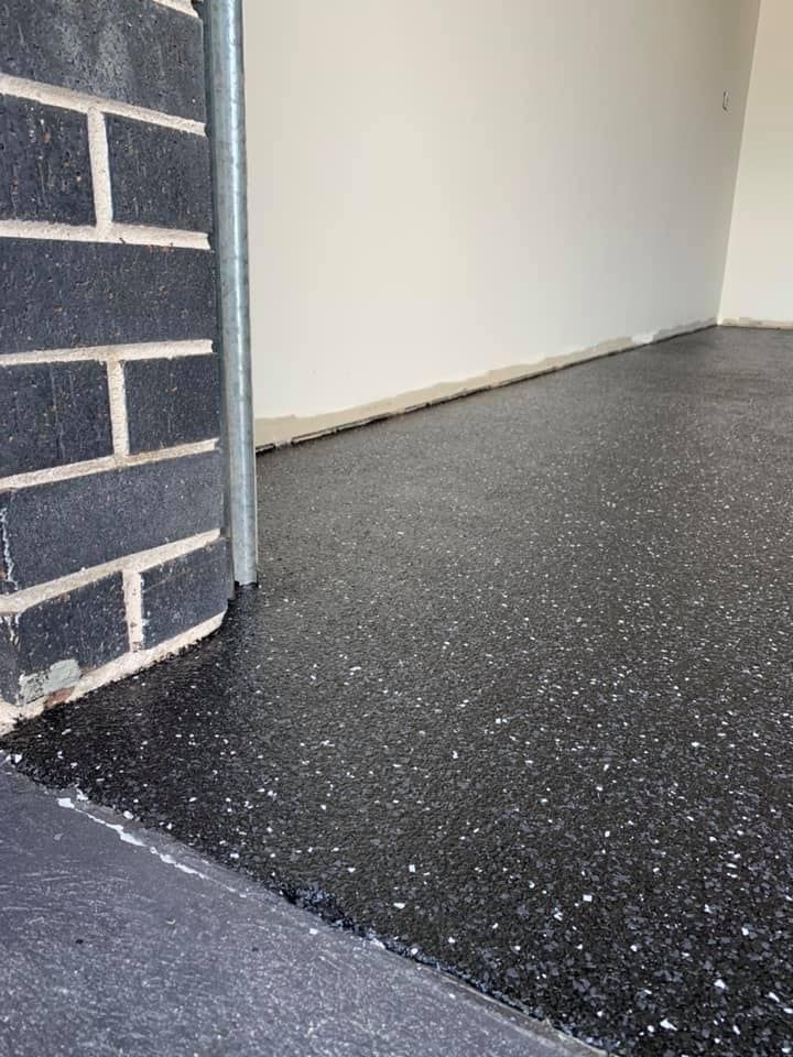 There is a brick wall in the background and a black floor in the foreground. — Partlic Painting & Epoxy Flooring In Wingham, NSW