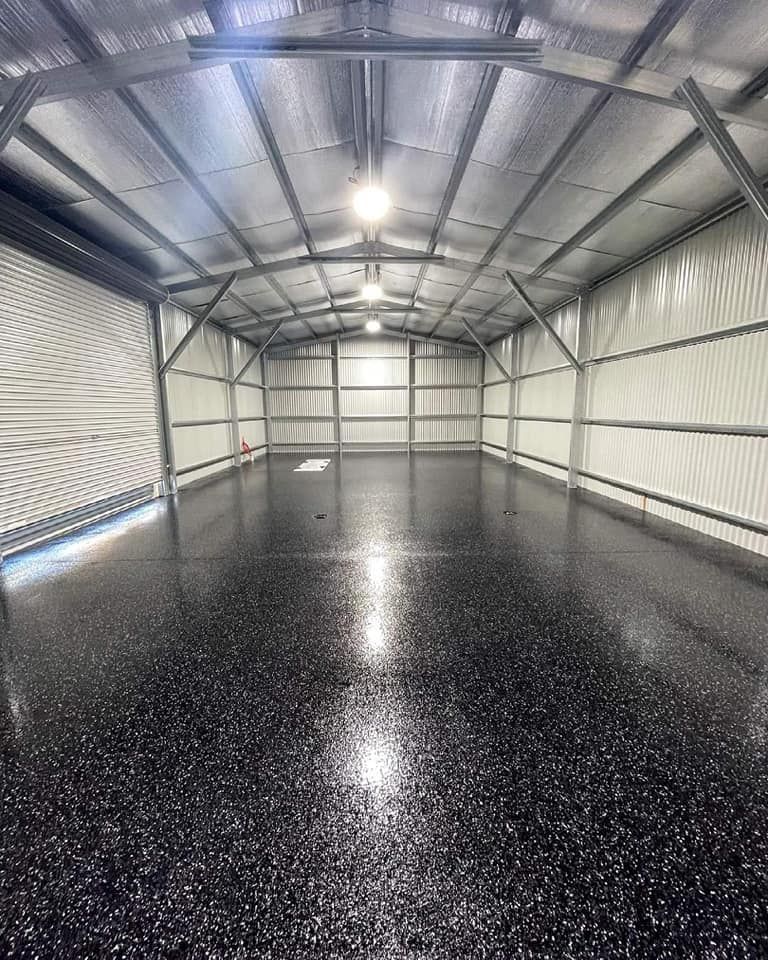 A Large Empty Garage With A Black Floor And White Walls — Partlic Painting & Epoxy Flooring In Taree, NSW