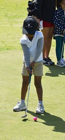 Golfer putting on a green, crouched over the ball with putter in hand.