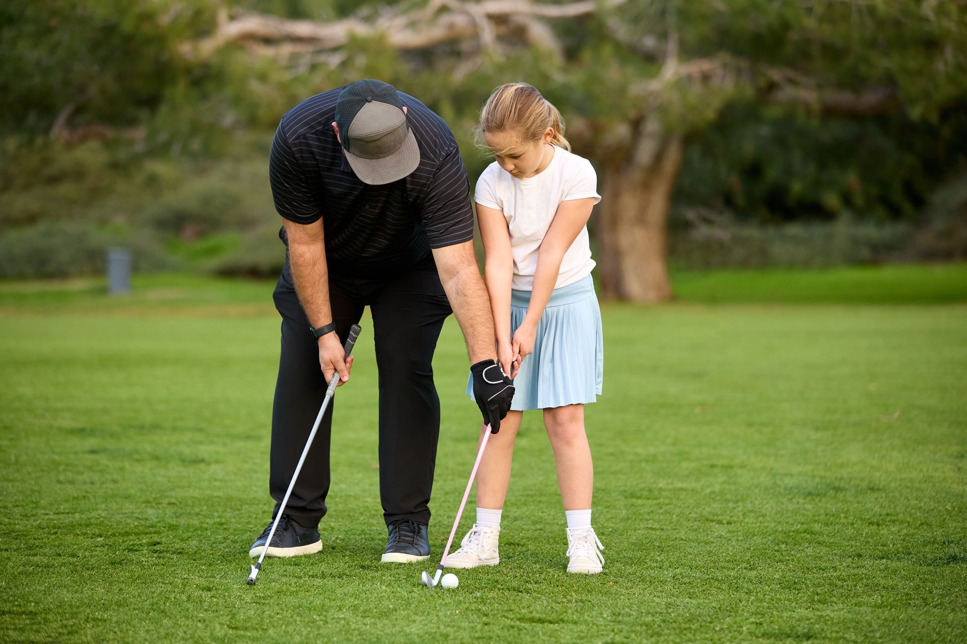 Two golfers putting on a green, one adult and one child, both focused on their strokes Two golfers putting on a green, one adult and one child, both focused on their strokes