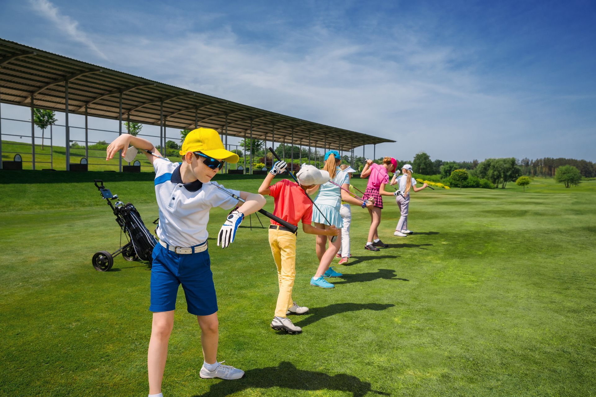 Golfers stretching on a green course near a covered practice area