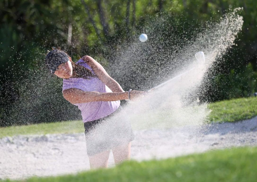 Golfer in purple shirt splashes through a water hazard, spraying water high into the air. Golfer in purple shirt splashes through a water hazard, spraying water high into the air.