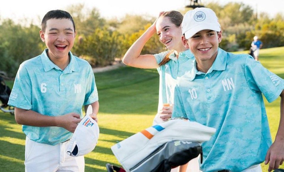 Golfer in orange shirt swinging a club on a sunny golf course