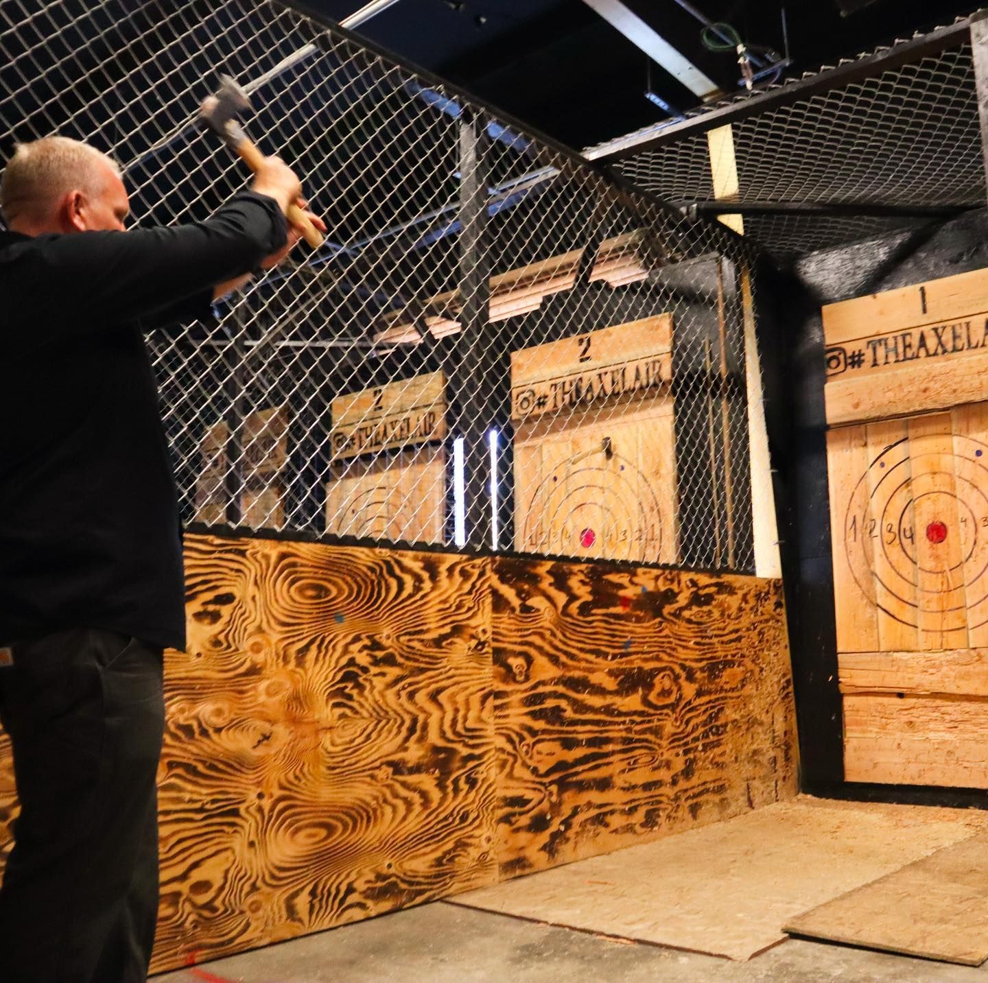 Person throwing an axe at a target in an indoor axe-throwing range