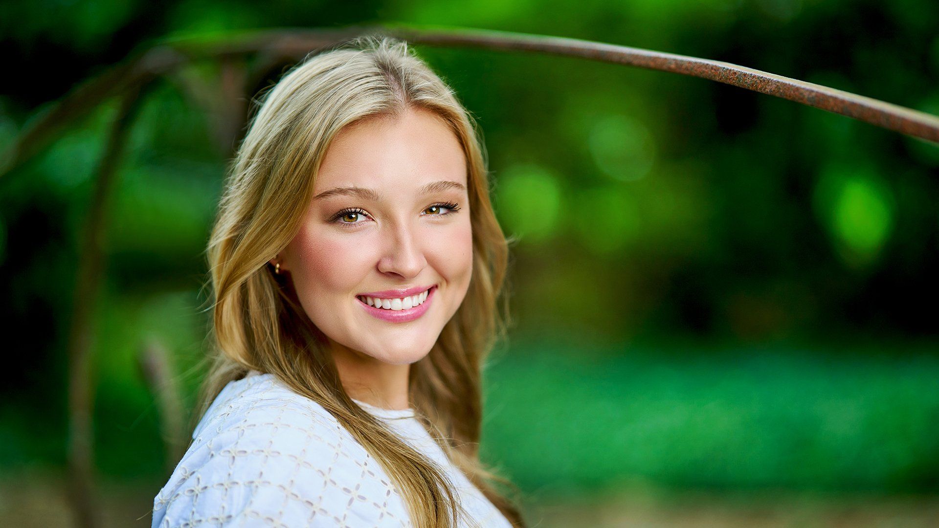 A young woman in a white sweater is smiling for the camera.